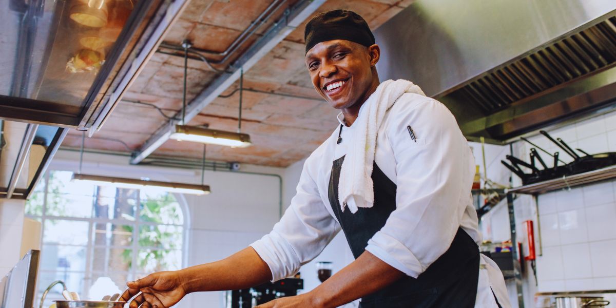 Mains d’un cuisinier dressant une assiette de poisson grillé sur un plan de travail